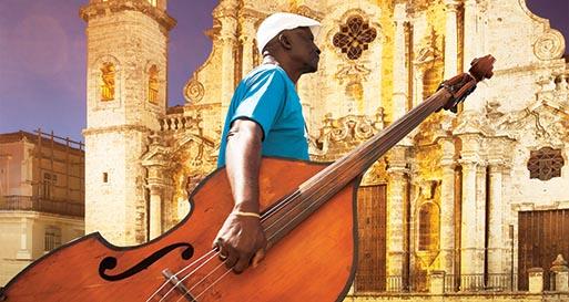 Hispanic musician carrying upright bass near church, Havana, Cuba